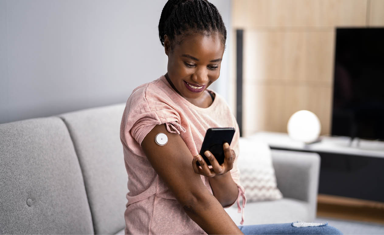 Woman Testing Glucose Level With Continuous Glucose Monitor On Mobile Phone