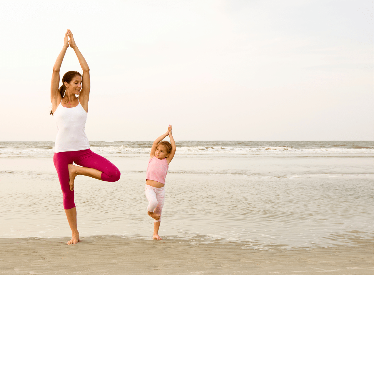 Mother teaches daughter yoga on beach